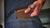A man puts a brown leather wallet in his jean pocket.