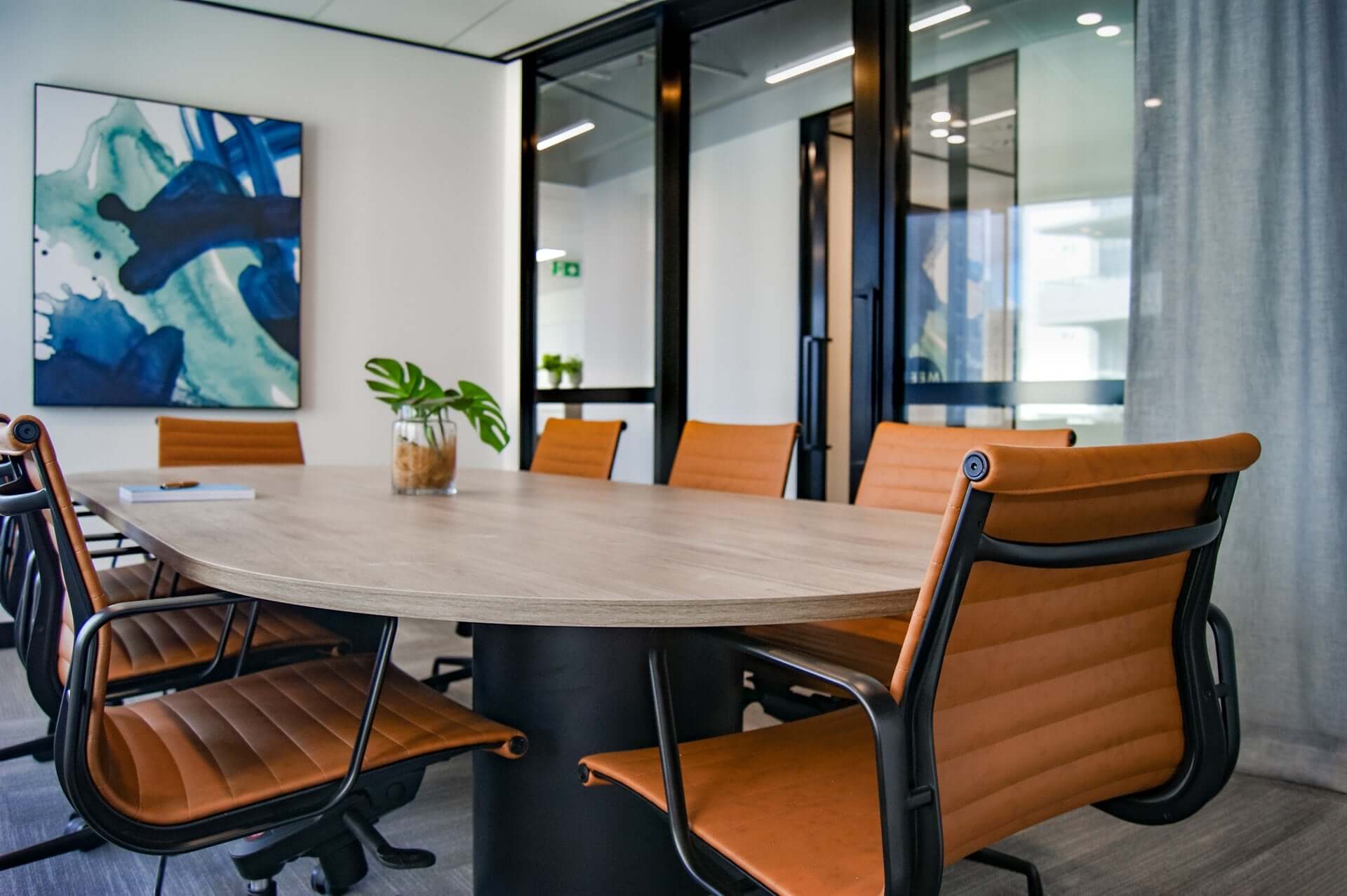 An office meeting room with light brown leather chairs and a light tabletop. 