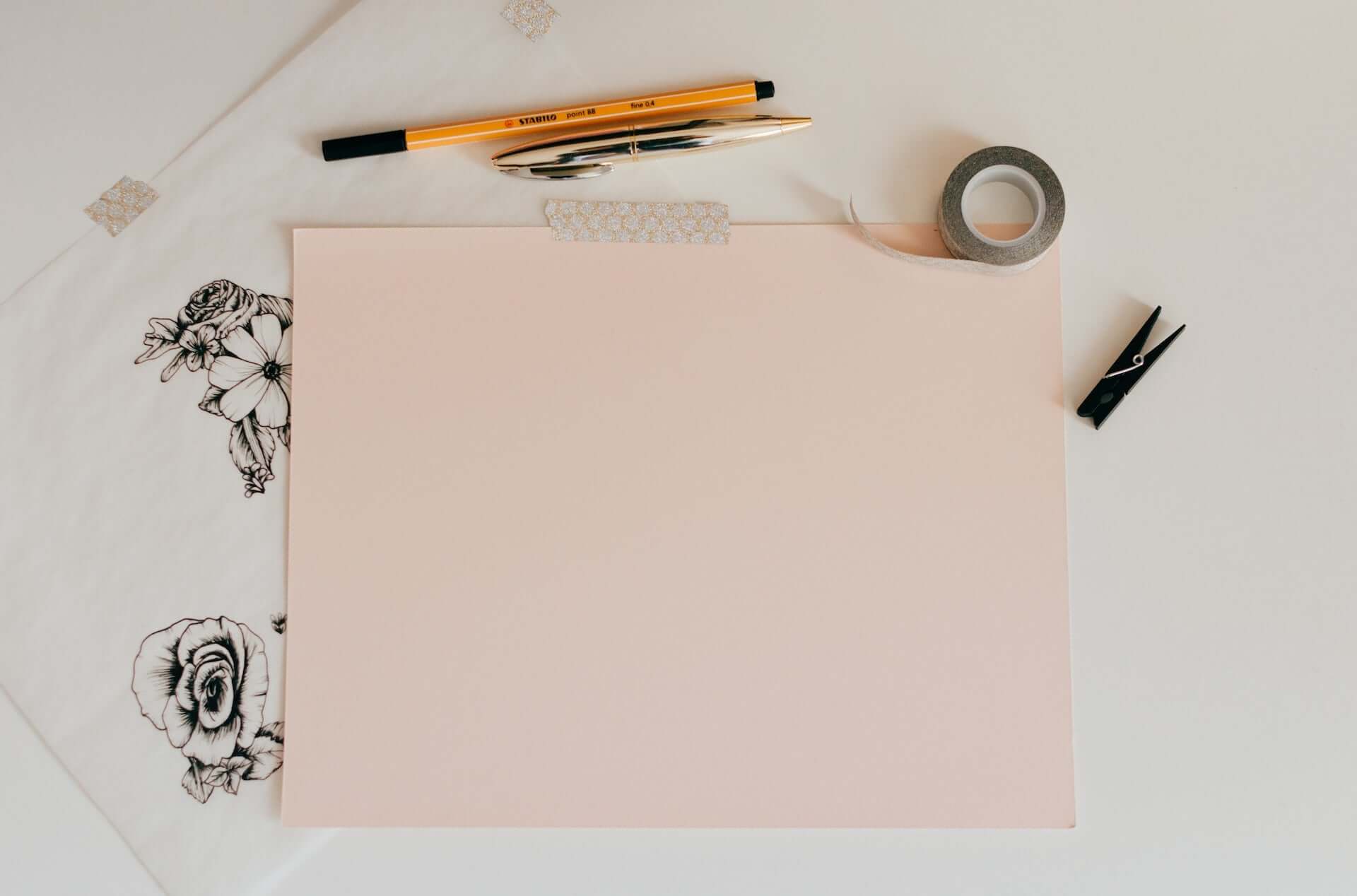 A pink piece of paper surrounded by art supplies.
