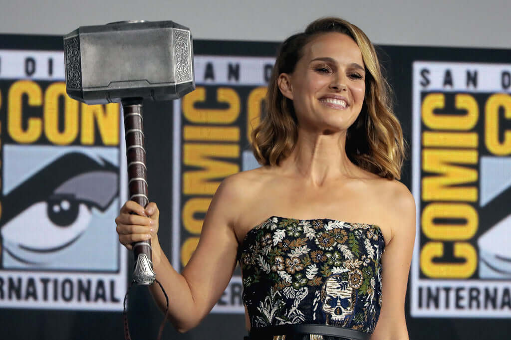 Natalie Portman at Comic Con holding up Thor's hammer.