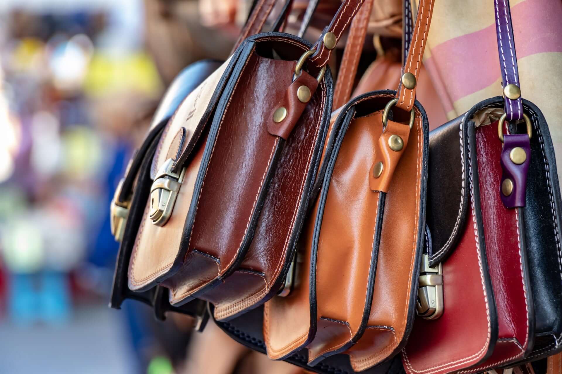 A set of three multicolored leather handbags.