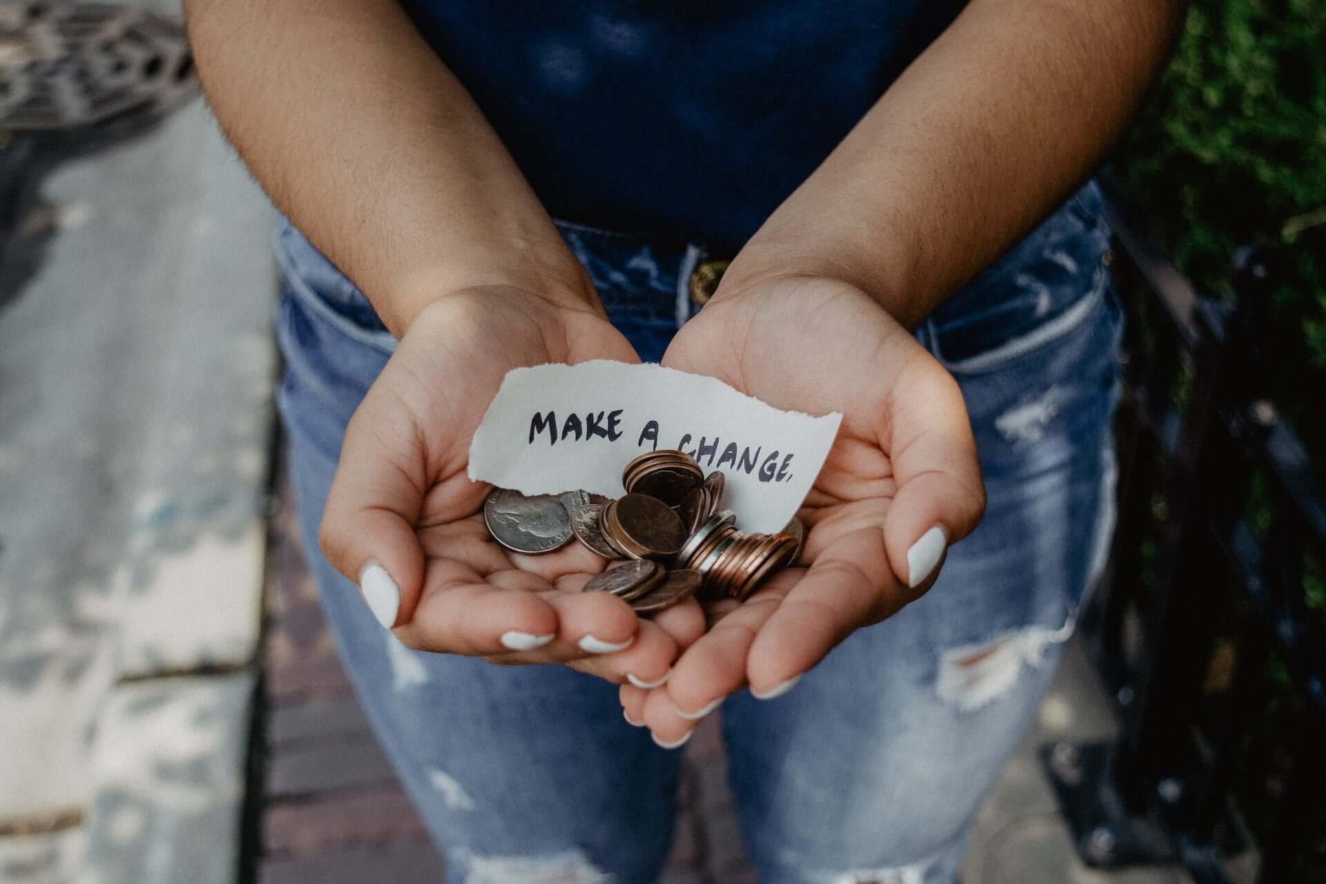 A person holding American coins in cupped hands with a note that reads "Make a Change."