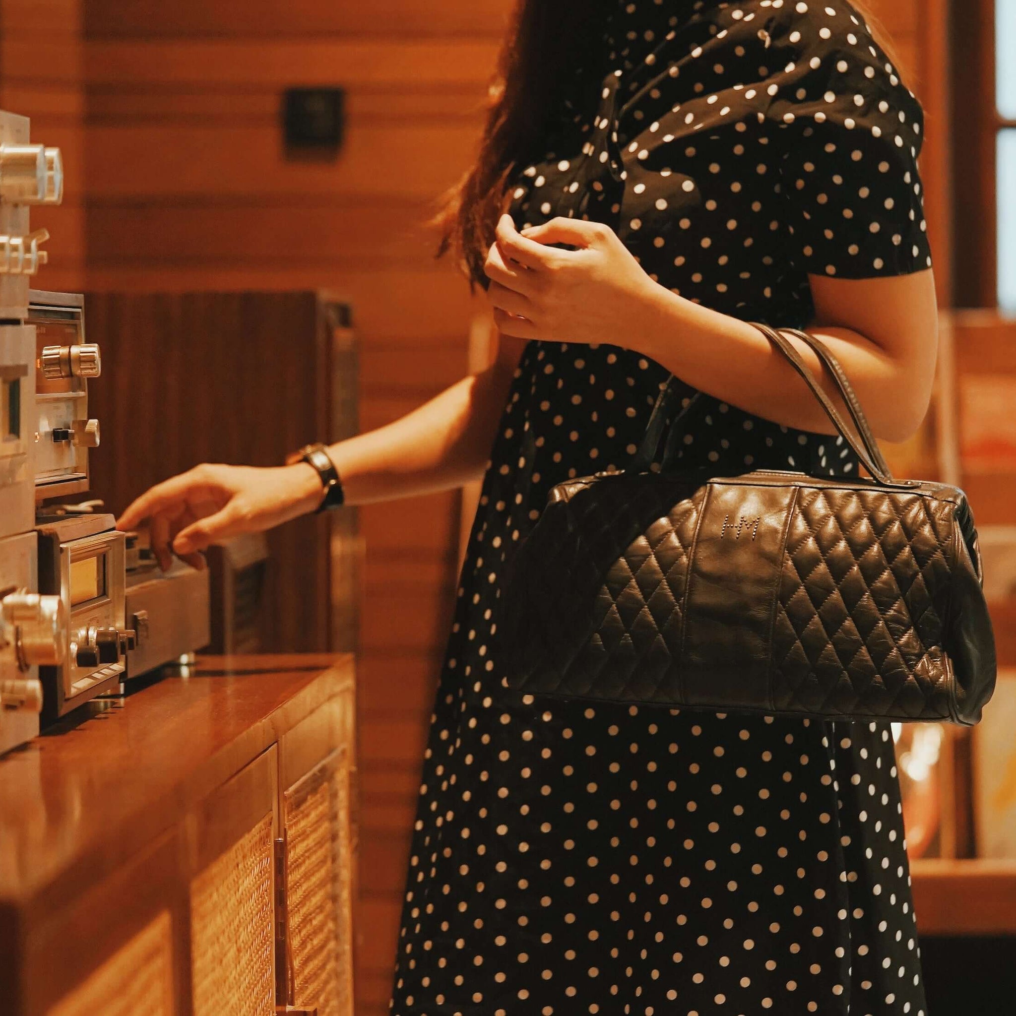 A cutoff picture of a woman carrying a small black bag. She is using a radio.