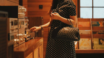 A cutoff picture of a woman carrying a small black bag. She is using a radio.