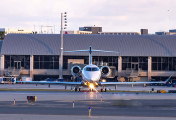 A head-on view of an airplane in front of a small airport.