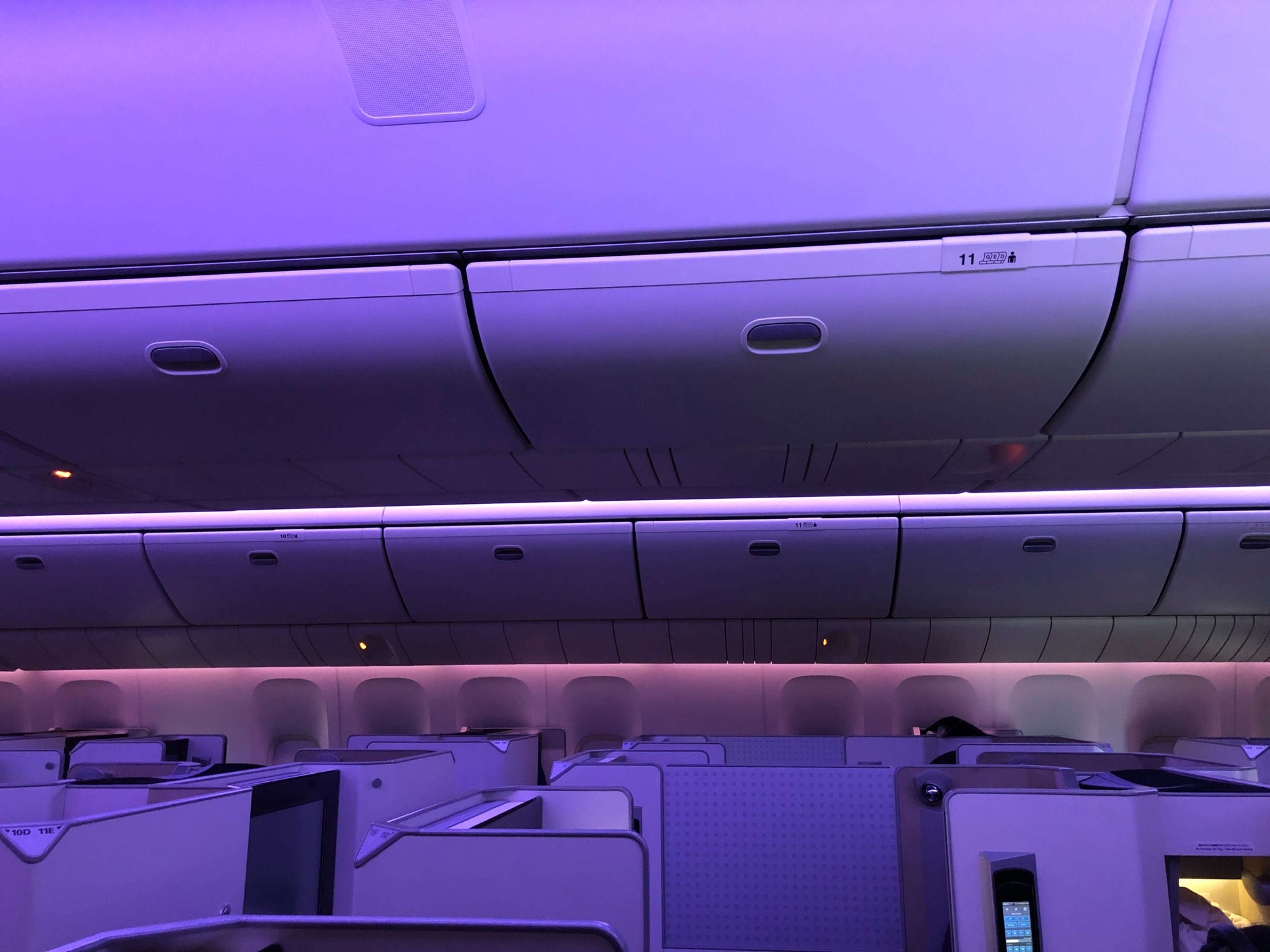 A purple-tinted image of seats in the first class cabin of an airplane.