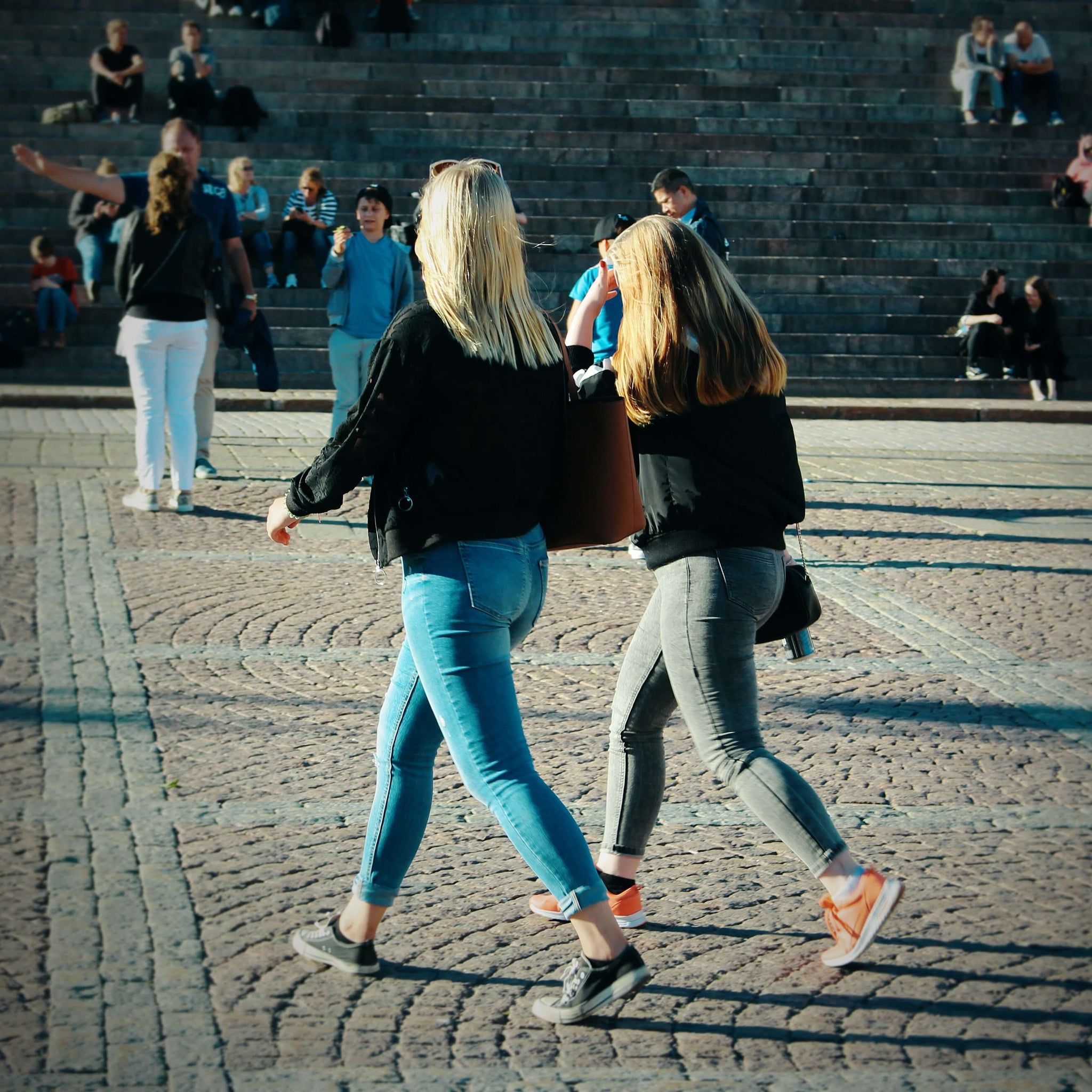 Two women walking in a city plaza.