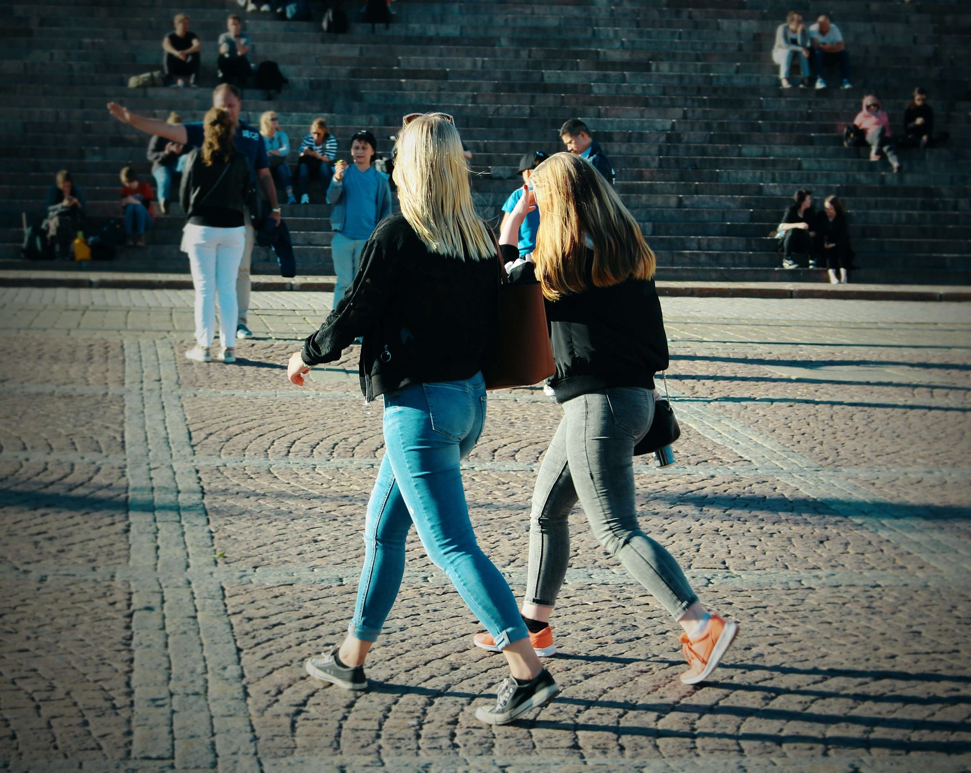 Two women walking in a city plaza.