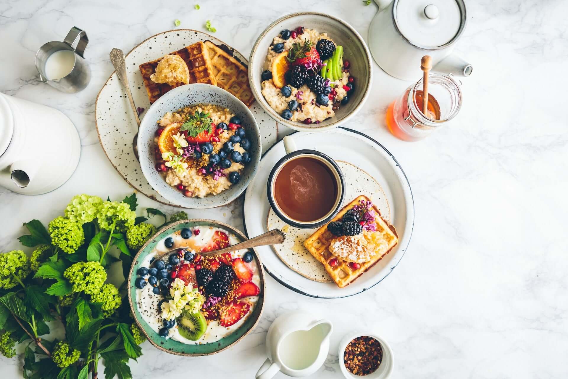 A spread of various brunch foods including fruit and waffles.