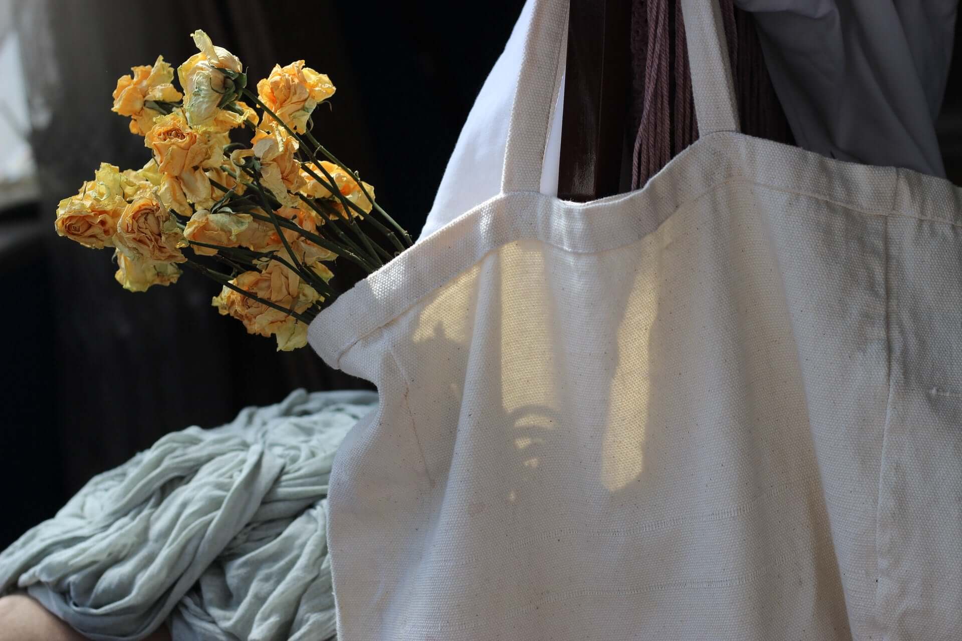 A white canvas tote bag holding yellow flowers.