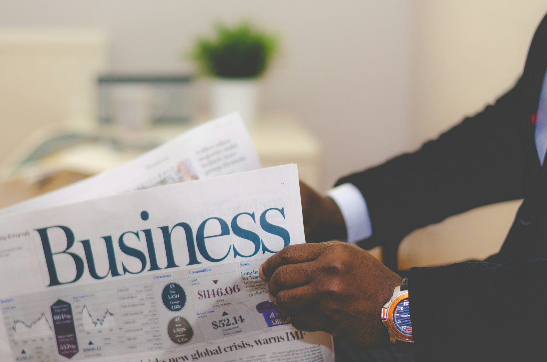 A man in a suit reading a business newspaper.