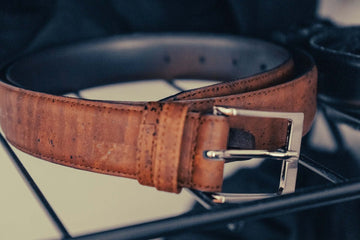 An old brown leather belt with a silver square buckle.