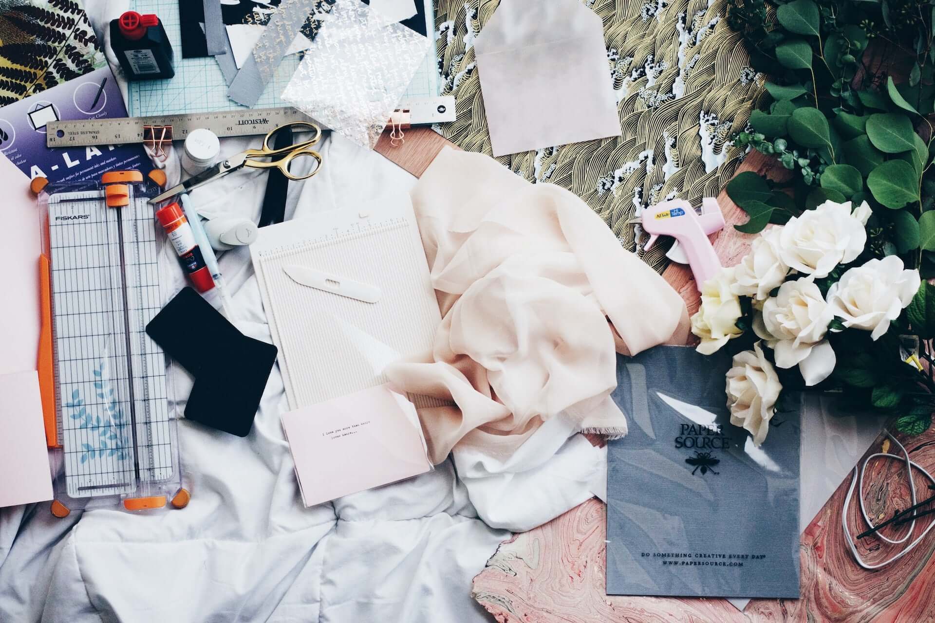 A table covered in sewing supplies and light pink fabric.