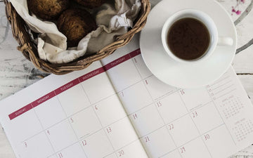 An open calendar book with a cup of coffee sitting on it.