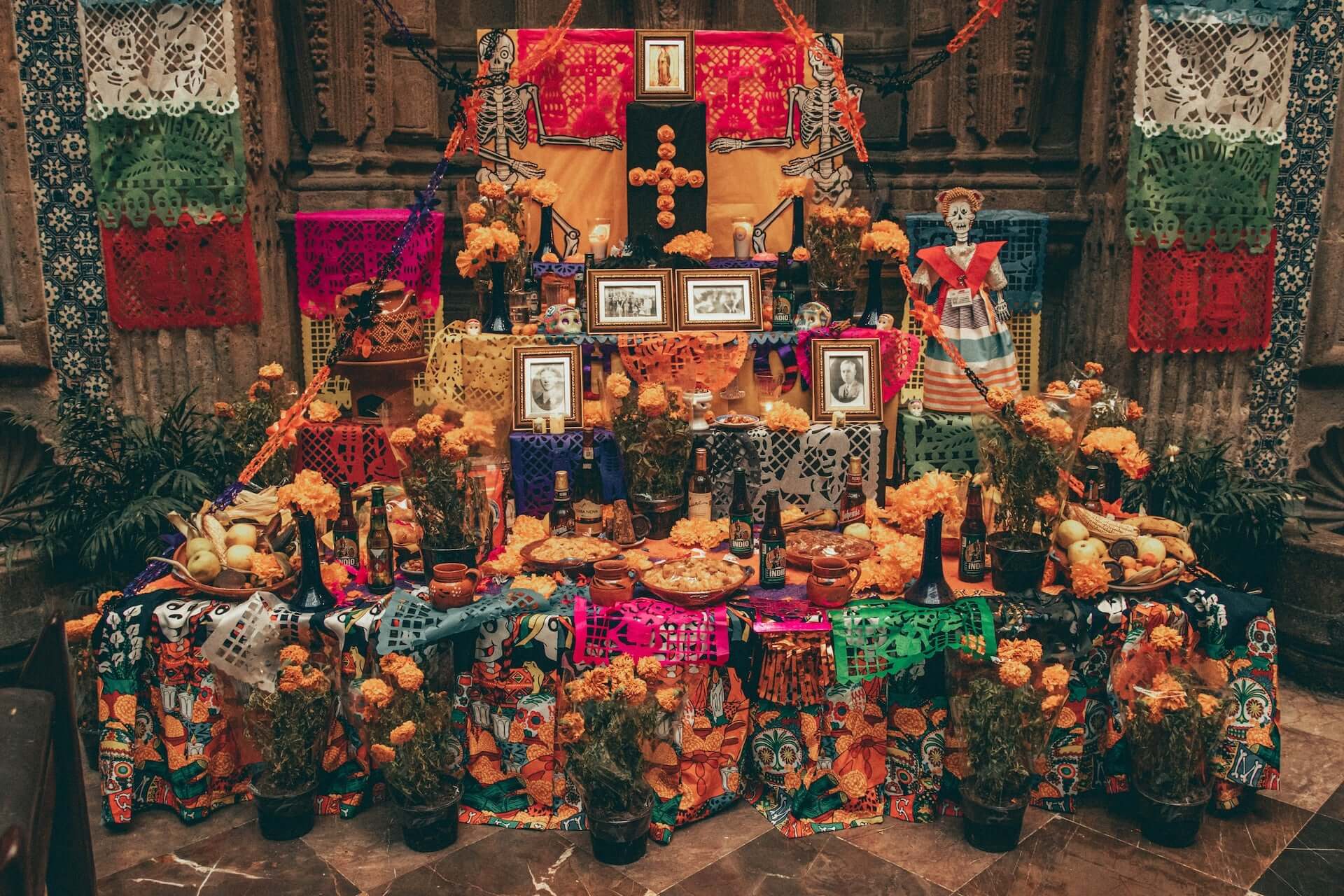 A Dia de los Muertos ofrenda full of flowers, food, and pictures of passed on loved ones.