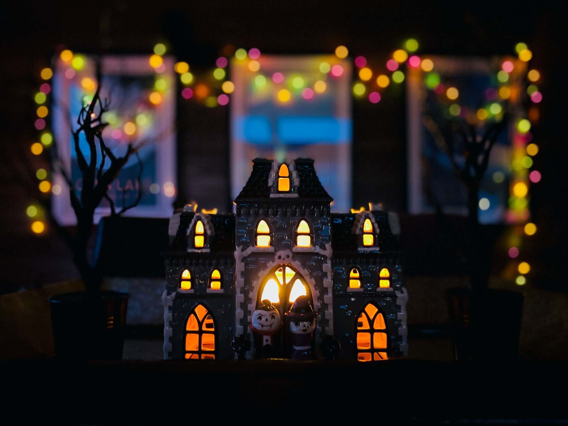 A small light-up haunted house surrounded by fairy lights.