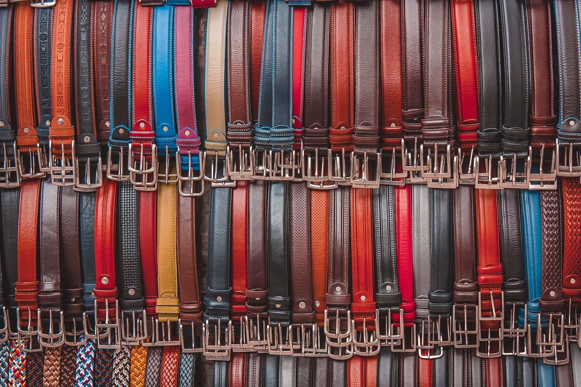 A wall of hanging belts in various colors and styles.