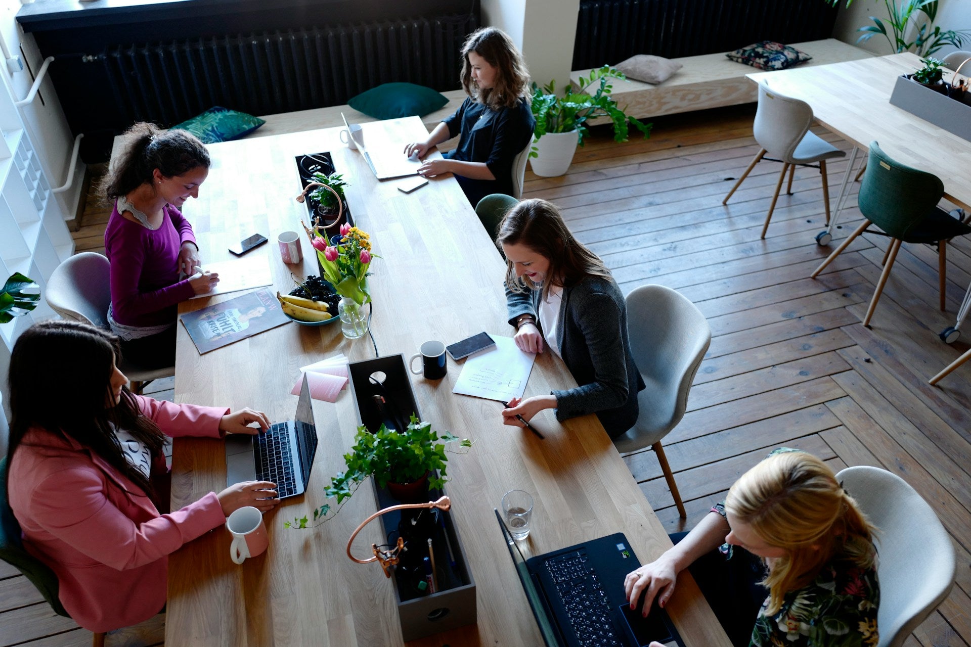 Women in a modern office setting, working around a large table.