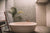 An earthtoned bathroom with an oval-shaped freestanding tub and a palm tree.