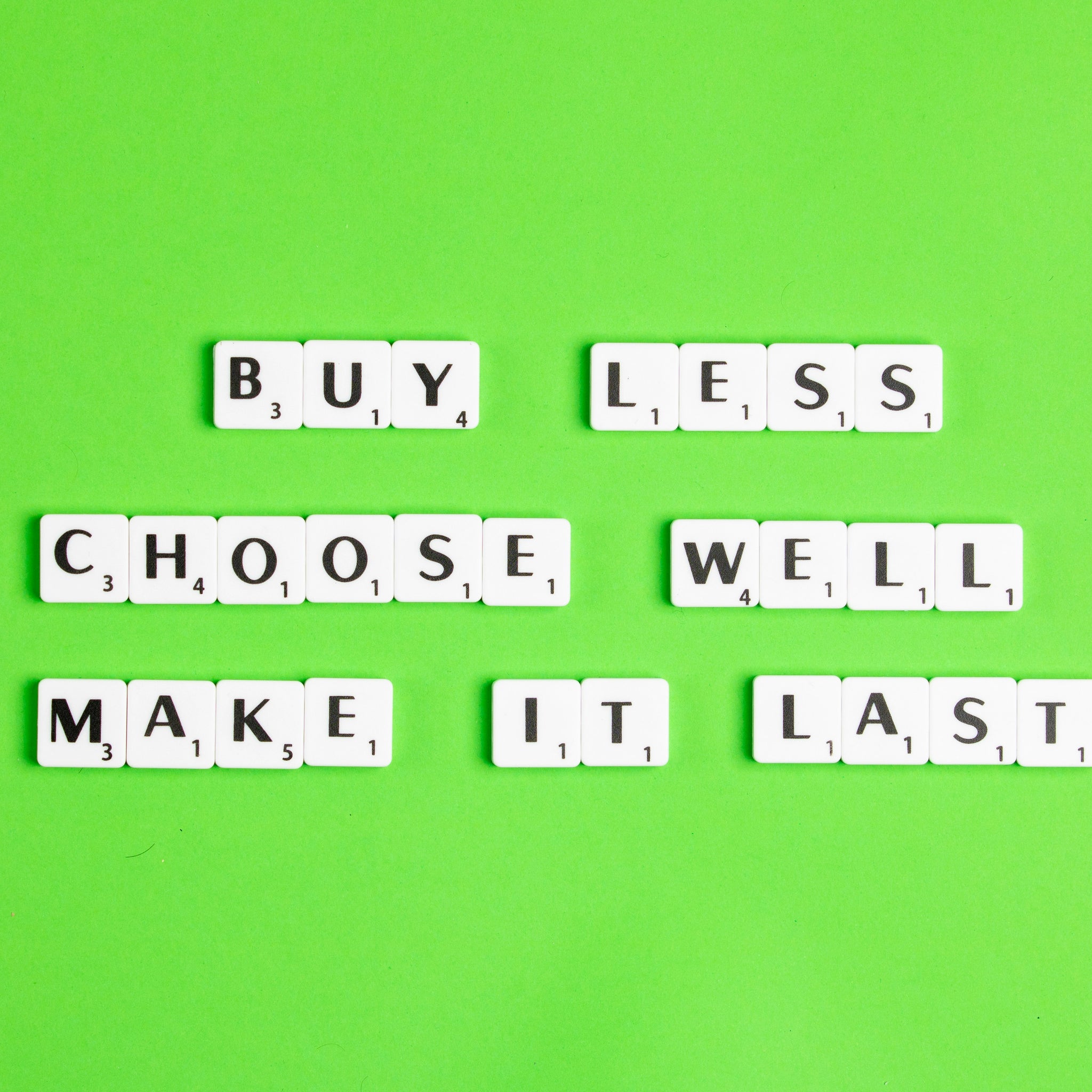 Letter tiles on a green background that spell out "Buy less, choose well, make it last."