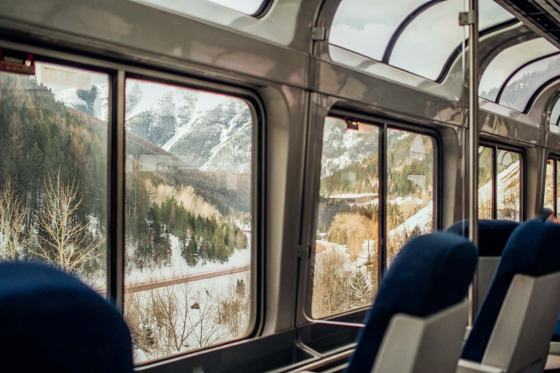 A view of snowy mountainsides from a train's viewing car.
