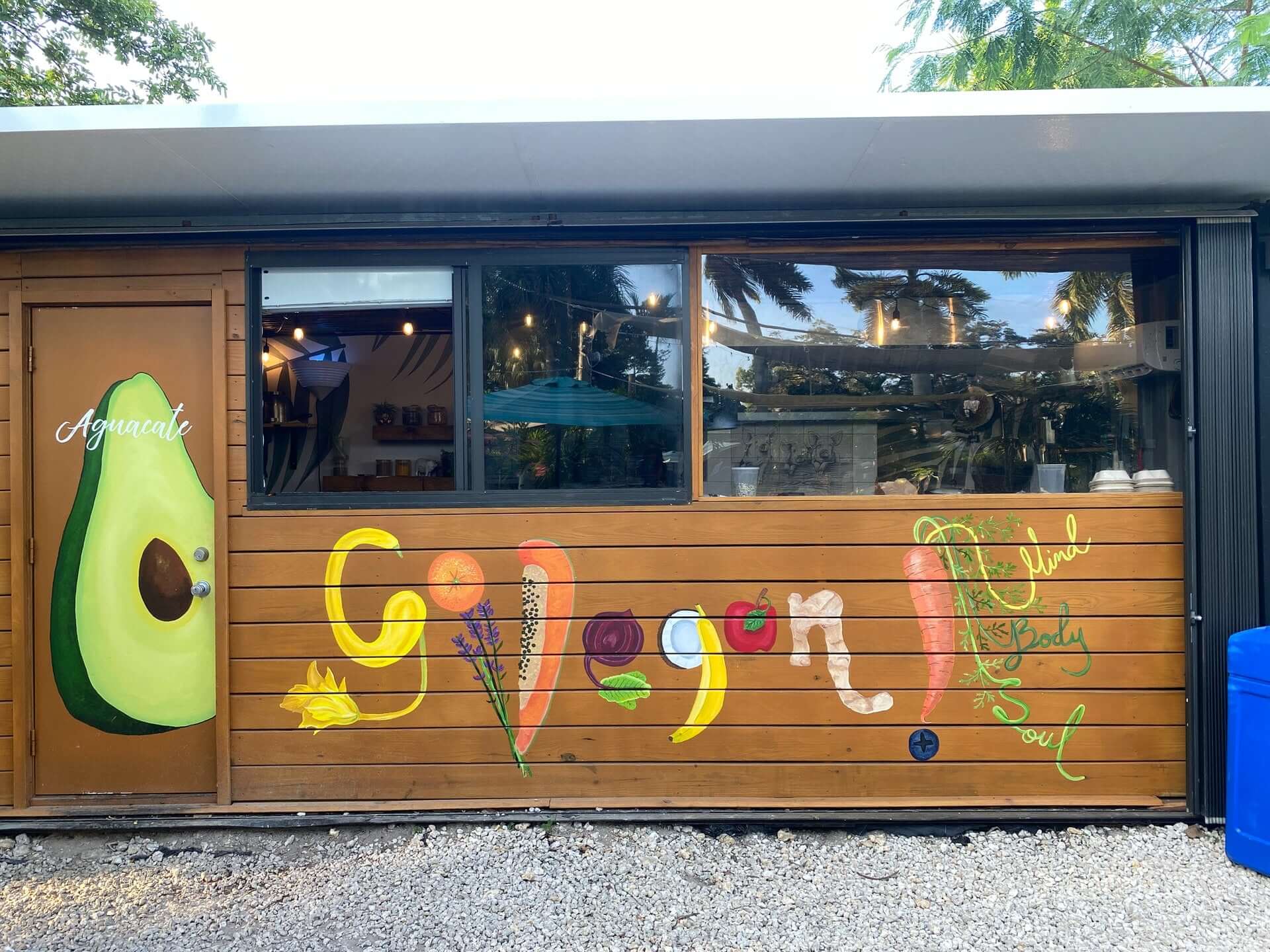 A brown paneled wall painted to say "Go Vegan." the words are assembled from different vegetables and fruits.