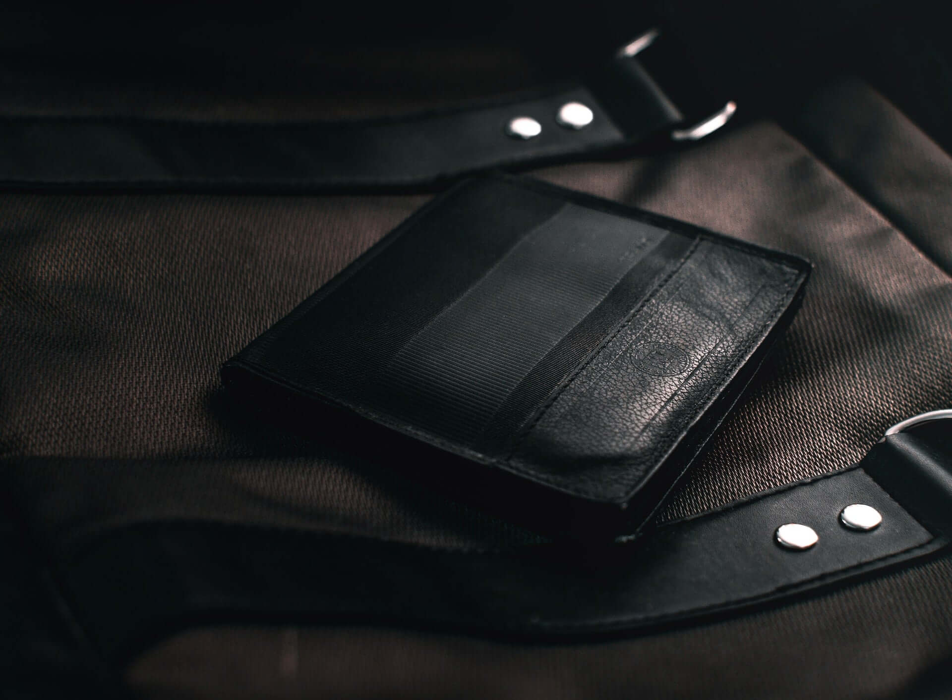A black wallet sitting on a black leather briefcase.
