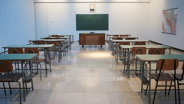 An empty classroom with two rows of double desks.