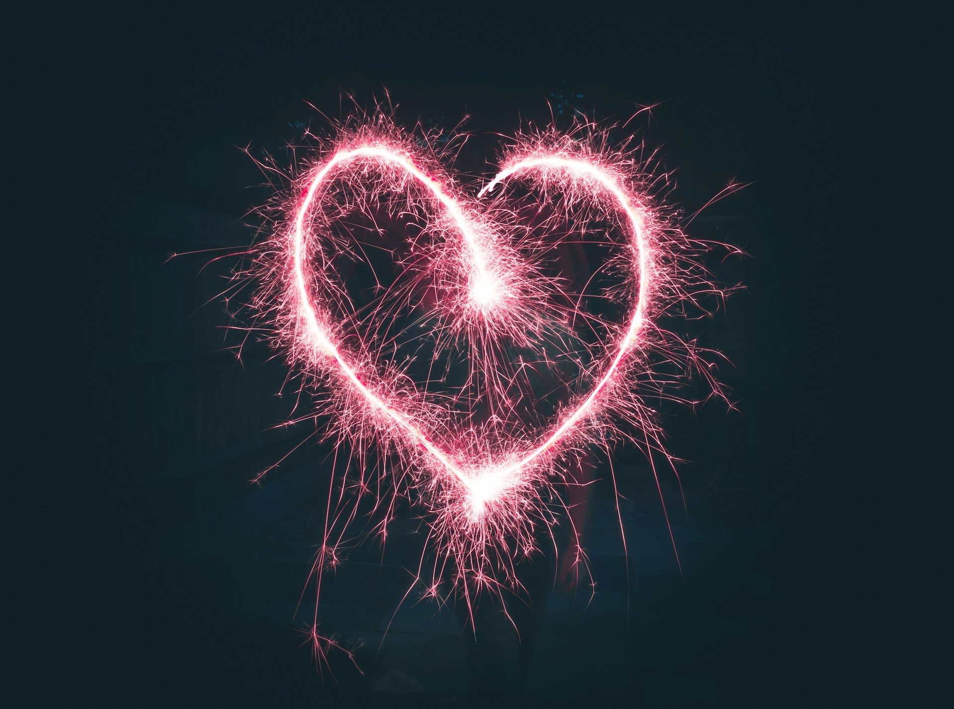 A pink heart made of sparkler sparks.