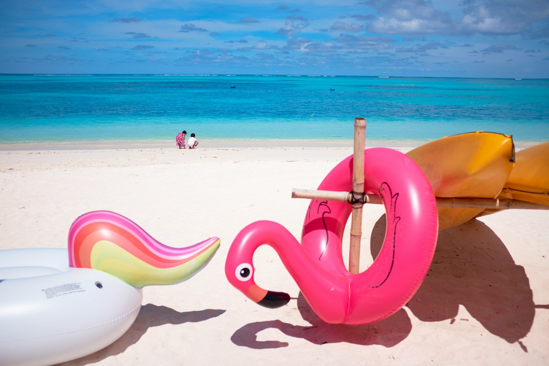 Pool floats shaped like a unicorn and a flamingo on a beach.