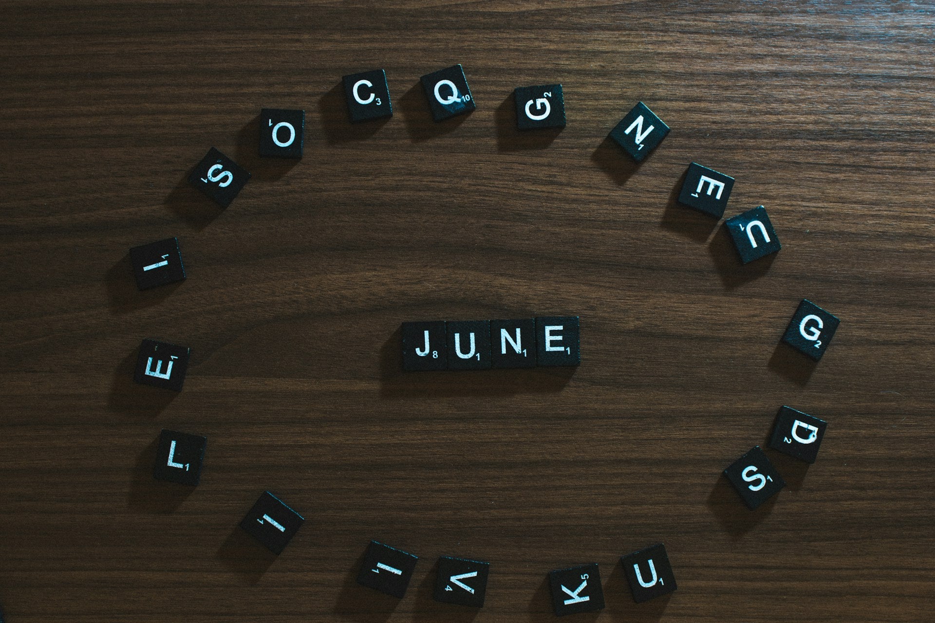 Letter tiles arranged in a circle around tiles that spell out "June."