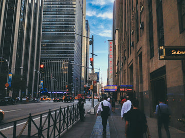 A street in a large city during the day. The streets are busy with people and cars.