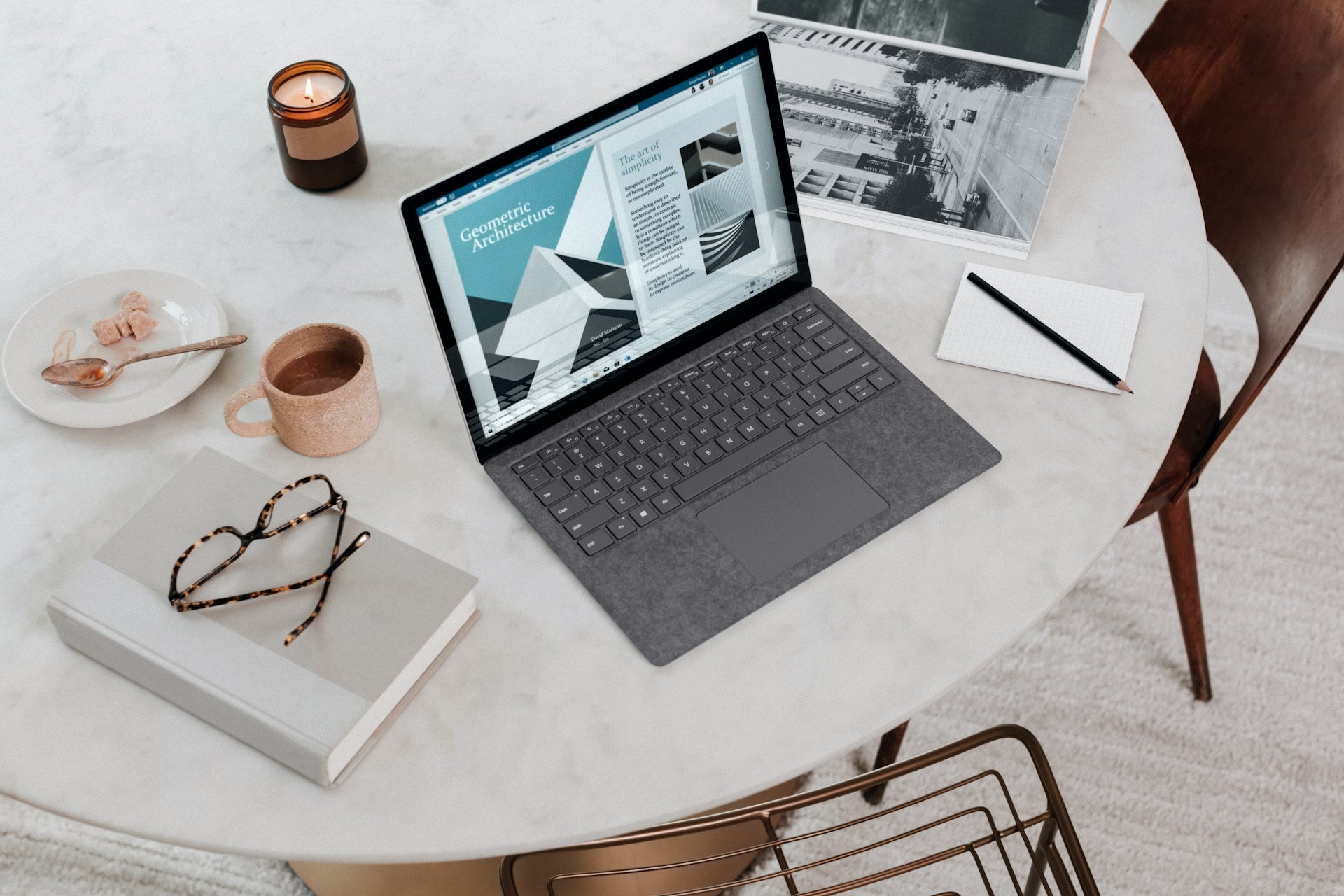 A laptop set up on a round table, surrounded by various business accessories.